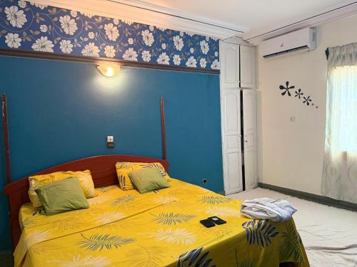 a bedroom with a yellow bed with a blue wall at RBNB by MELUSH in Cotonou