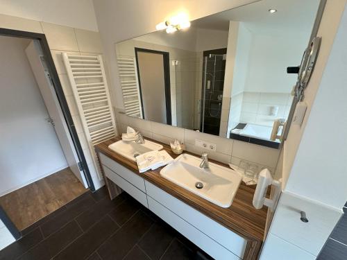 a bathroom with two sinks and a large mirror at Reit- und Sporthotel Eibenstock in Eibenstock