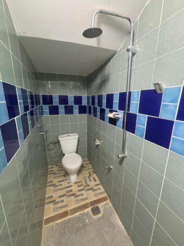 a bathroom with a toilet and blue tiles at Residence FATIMA in Thiès