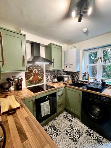a kitchen with green cabinets and a stove top oven at Avalon Sunrise our enchanting Glastonbury cottage in Glastonbury