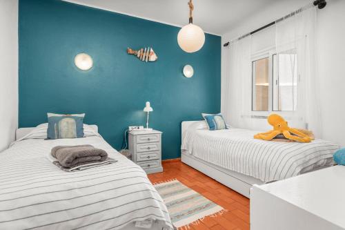 a bedroom with two beds and a blue wall at Casa Indie in Burgau