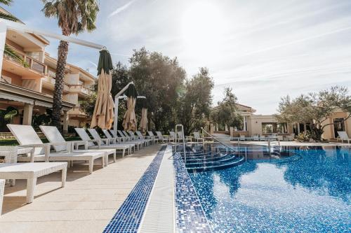 a pool at a hotel with chairs and umbrellas at Resort Trcol in Novalja