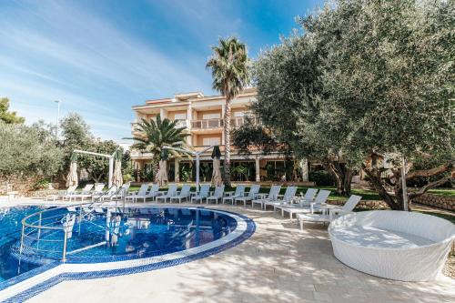 einen Pool mit weißen Stühlen und ein Gebäude in der Unterkunft Resort Trcol in Novalja