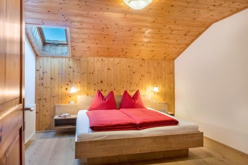 Un dormitorio con una cama con almohadas rojas. en Apartment Völs Gfliererhof, en Vols am Schlern