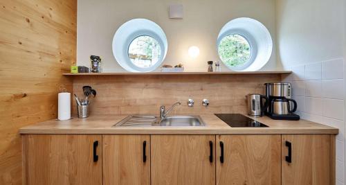 a kitchen with a sink and two circular windows at Berghotel Hammersbach, Sure Hotel Collection by Best Western in Grainau