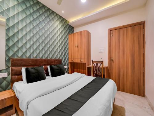 a bedroom with a large bed and a wooden cabinet at Hotel O Zamzam Residency in Bhopal