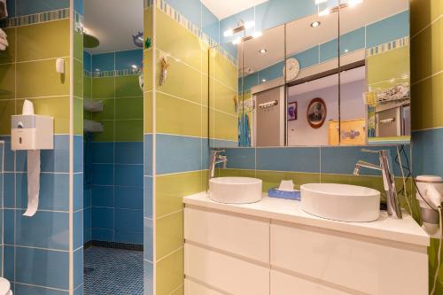 un bagno con due lavandini e piastrelle blu e gialle di Les pieds dans l'eau a Virebelle