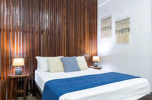 a bedroom with a bed and two tables with lamps at El Deseo Serendipity Tortuguero in Tortuguero