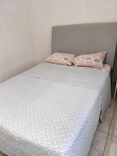 a white bed with two pillows on top of it at Mini lar próximo ao parque in Caparaó Velho