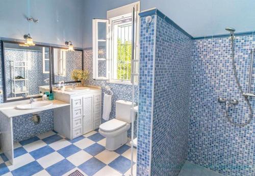 Un baño con azulejos azules, inodoro y lavabo. en Casa Rural Santa Ana, en Marchena