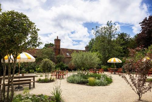 a garden with tables and chairs and umbrellas at The Swan Inn in Fittleworth