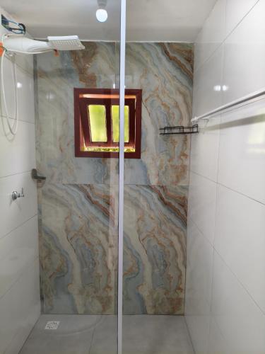 a shower with a glass door in a bathroom at Mini lar próximo ao parque in Caparaó Velho