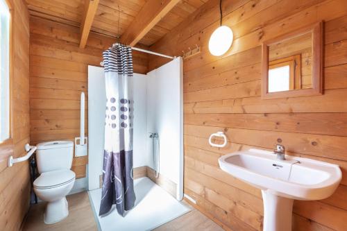 a bathroom with wooden walls and a toilet and a sink at Falaguera Barraca 2 in Bárig