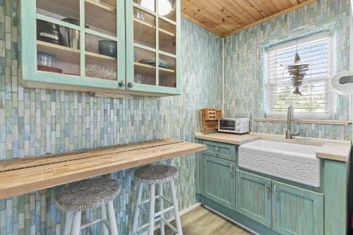 a kitchen with green cabinets and a sink and stools at Terrapin Station I in Chicken Island