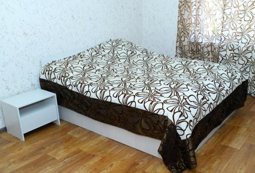 a bed with a black and white blanket and a table at Vardanyan Family Guest House in Shnogh