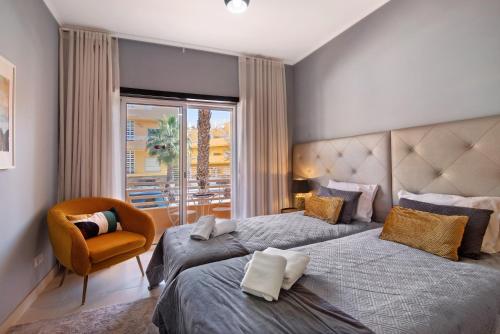 a bedroom with two beds and a chair and a window at Apartamento Royal Cabanas Golf in Conceição