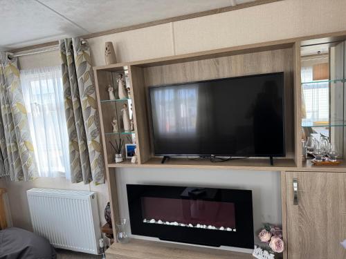 ein Wohnzimmer mit einem Flachbild-TV und einem Kamin in der Unterkunft Sutherland C14 in Lossiemouth