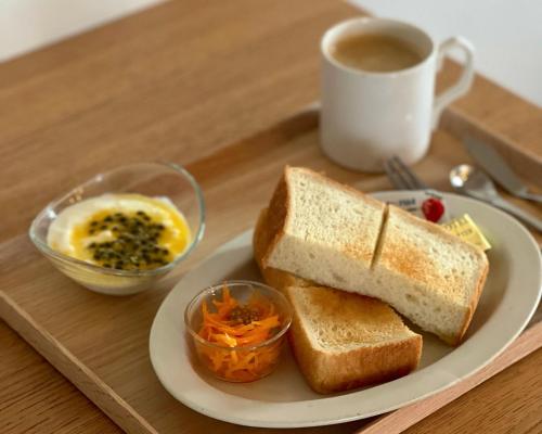 un plato con un sándwich y una taza de café en Holly Camp Airstream Villa Amami, en Amami