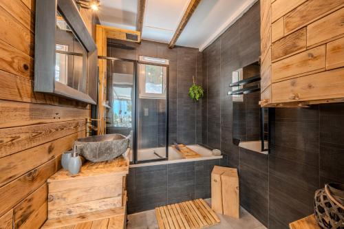 a bathroom with a tub and a shower with wooden walls at Maison vue mer avec piscine in Plouider