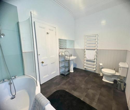 a bathroom with a tub and a toilet and a sink at Dungora House in Crieff