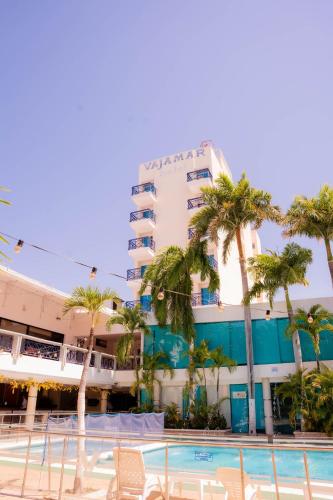 a hotel with palm trees in front of a pool at GIO Hotel Vajamar Valledupar in Valledupar