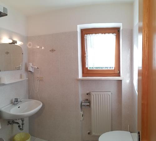 a bathroom with a sink and a toilet and a window at Ferienwohnung Valentin in Meltina