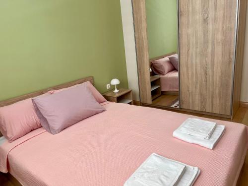 1 dormitorio con cama rosa y espejo en Urban Taft Stay Skopje-Vodno View Suite with Underground Parking, en Skopje