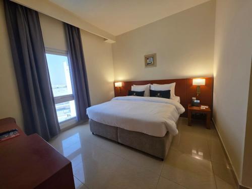 a bedroom with a large bed and a large window at Acacia Hotel by BP Management in Ras al Khaimah