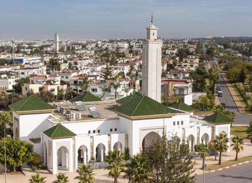 a large white building with a tower in a city at Pearl Rabat Stay 75 TV POOL in Rabat