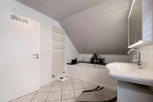 シュライデンにあるFerienhaus Oleftal Nationalparkの洗面台と浴槽のある白いバスルーム