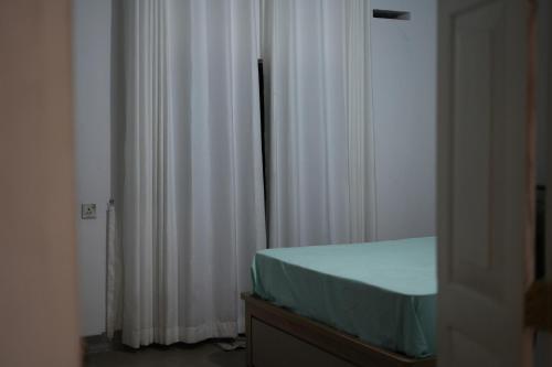 a bedroom with a bed and white curtains at Sri Vishwa Buddha MUni in Kalagedihena