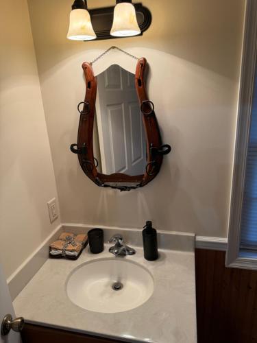 une salle de bain avec un lavabo et un miroir chauve-souris dans l'établissement The Saloon Cabin Retreat, à Hedgesville