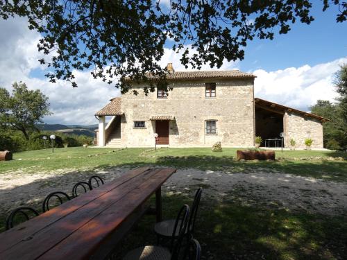 Una mesa de picnic de madera frente a un edificio de piedra. en CASALE AL LAGO con PISCINA E SAUNA, en Corbara
