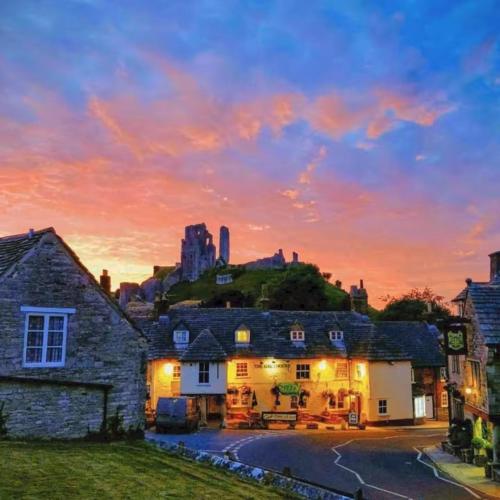 a house with a sunset in the background at Castle View Suite - Corvesgate Cottage - 3 room suite in Corfe Castle