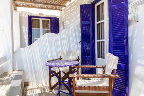 a porch with a blue door and two chairs and a table at Sorokos Koufonissia in Koufonisia