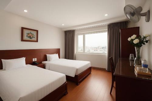 a hotel room with two beds and a window at Van Ha Boutique Hotel Etown - Nhà Ga T3 in Ho Chi Minh City