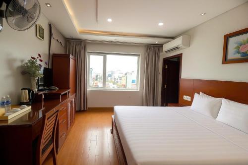 a bedroom with a bed and a desk and a window at Van Ha Boutique Hotel Etown - Nhà Ga T3 in Ho Chi Minh City