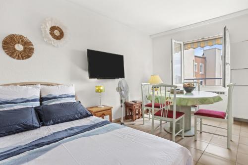 una camera da letto con un letto, un tavolo e una TV di Appartement deux pas de la Mer a Fréjus