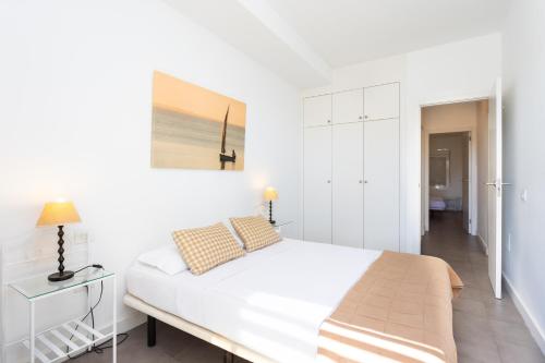 a white bedroom with a large bed and a table at Eden Rentals Pure Abona in Poris de Abona