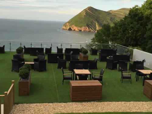 a group of tables and chairs on a lawn with the ocean at Sandy Cove Hotel in Ilfracombe