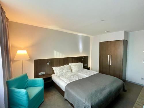 a bedroom with a bed and a blue chair at Elegantes Smart Apartment in Szene-Viertel in Düsseldorf