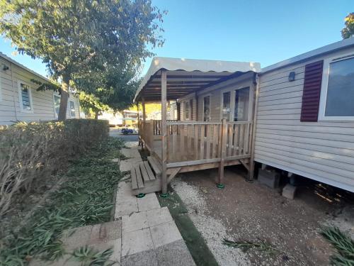 une petite maison avec un porche et une terrasse dans l'établissement FMLODGE- sables du midi mobilhome les glycines, à Valras-Plage