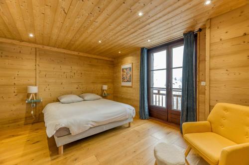 a bedroom with a bed and a chair and a window at Le Flocon Grand Chalet 4 étoiles in Villard-Reculas