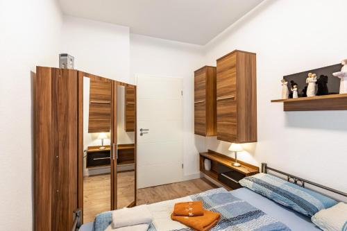 a small bedroom with a bed and wooden cabinets at Fewo am Georgengarten - Wohnung 1 in Dessau