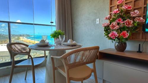 Un comedor con una mesa con un jarrón de flores. en Art Studio Incredible roofop by VLV Stays, en Salvador
