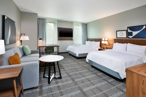 a hotel room with two beds and a couch at Staybridge Suites Grand Rapids South by IHG in Grand Rapids