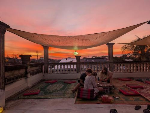 a group of people sitting on a balcony watching the sunset at Monkey Guesthouse - Savannakhet in Savannakhet