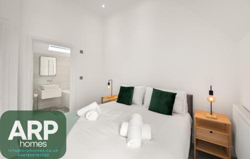 a bedroom with a white bed with green pillows at Spacious 3bd l Family Home in Coulsdon