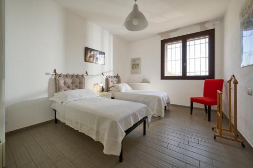 1 dormitorio con 2 camas y silla roja en La Casa Rossa, en Piombino