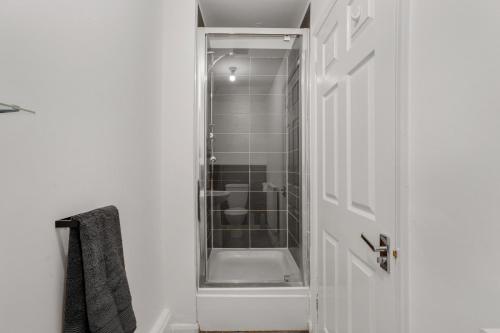 een badkamer met een douche en een witte deur bij Bright 1-Bed Flat, Near Station, Fast Wi-Fi in Wellingborough